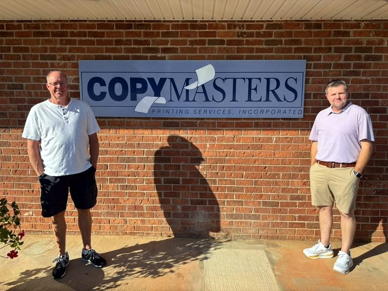 Jimmy and Billy outside the shop, under the CopyMasters sign on the brick wall